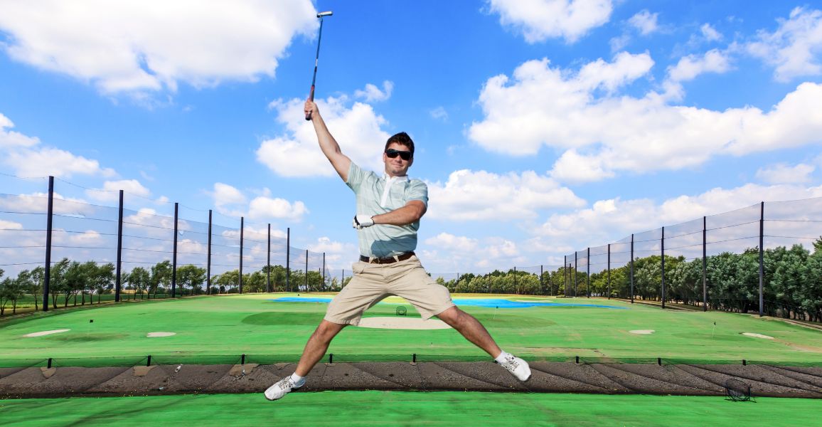 Man jumping in the air on the driving range because he is practicing