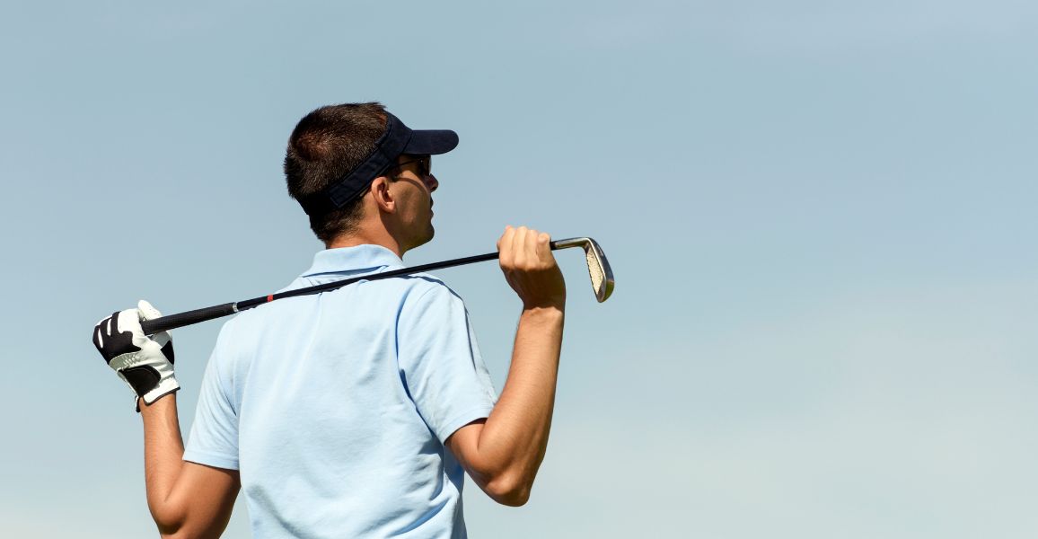 Golfer taking in the shot he just hit with a golf club behind his back