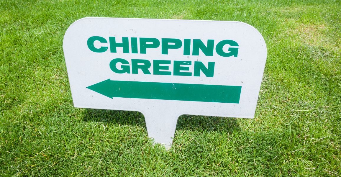 White steaked sign pointing towards a chipping green
