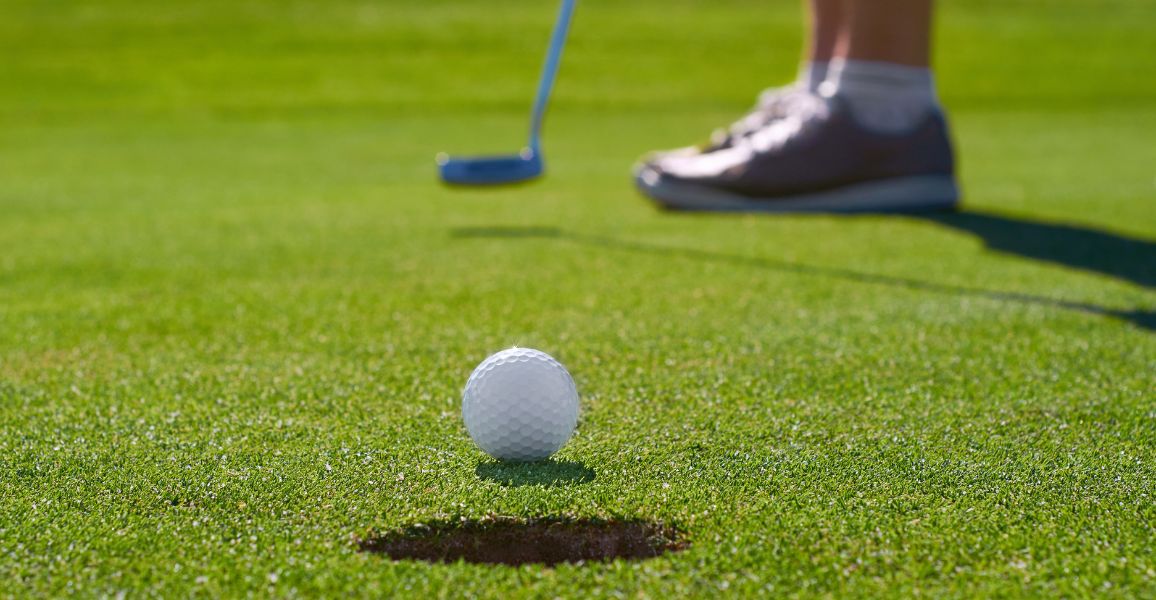 Golf ball about to go into the hole on a putting green after been hit by a golfer
