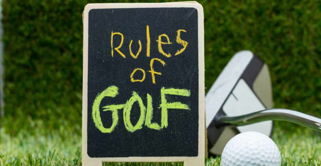 Chalk board that has the rules of golf on it with a putter and golf ball 