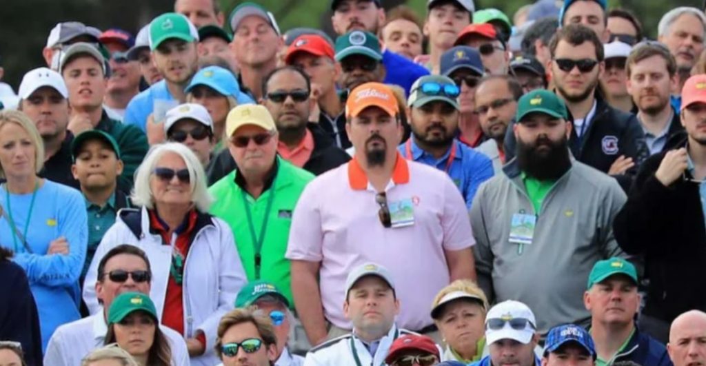 crowd of golf fans watching a golfer strike the golf ball