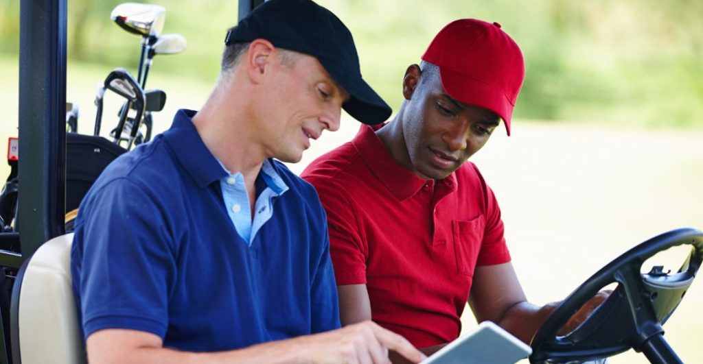 Golf instructor in blue giving tips to a golfer in red