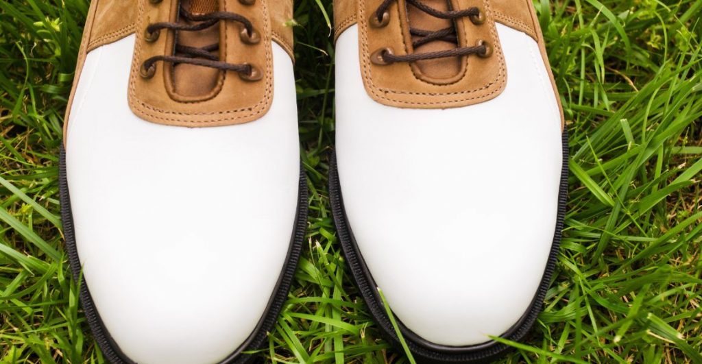 white leather golf shoes on the green grass