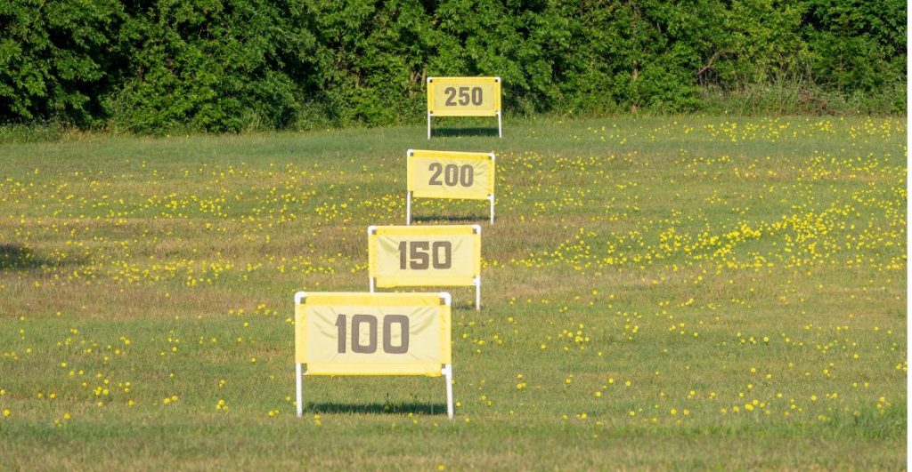 a driving range with yellow signs showing the distances